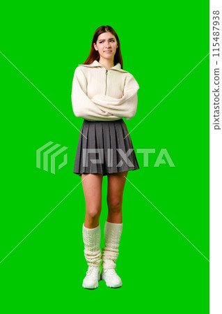 Smiling Young Woman Posing in Stylish Outfit Against Green Background 115487938