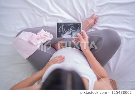 A portrait of happy Asian pregnant woman in bedroom at home with baby ultrasound. Having a baby. Family people lifestyle. Mom love. 115488062