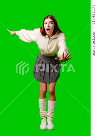 Young Woman Gesturing Excitement in Casual Attire Against Green Screen Backdrop 115488173