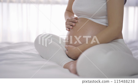 A Portrait of happy Asian pregnant woman in bedroom at home. Having a baby. Family people lifestyle. Love. A Portrait of happy Asian pregnant woman in bedroom at home. Having a baby. Family people lifestyle. Love. 115488238