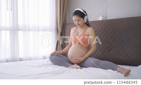 A portrait of happy Asian pregnant woman in bedroom at home. Having a baby. Training workout. Exercise indoor with sport equipment. Athletic. Family people lifestyle. Mom love. Recreation. 115488345
