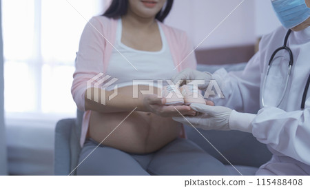 A portrait of happy Asian pregnant woman checkup with a doctor in bedroom at home. Having a baby. Family people lifestyle. Mom love. 115488408