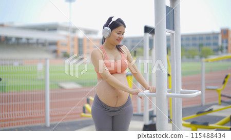 A portrait of happy Asian pregnant woman at gym fitness center club. Having a baby. Training workout. Exercise indoor with sport equipment. Athletic. Family people lifestyle. Mom love. Recreation. 115488434