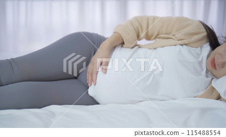 A Portrait of happy Asian pregnant woman in bedroom at home. Having a baby. Family people lifestyle. Love. A Portrait of happy Asian pregnant woman in bedroom at home. Having a baby. Family people lifestyle. Love. 115488554
