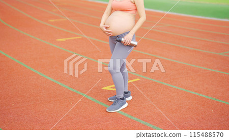 A portrait of happy Asian pregnant woman running on rubber floor, track on a sports stadium. Sport and recreation background. Having a baby. Family people lifestyle. Mom lifestyle. A portrait of happy Asian pregnant woman running on rubber floor, track on a sports stadium. Sport and recreation background. Having a baby. Family people lifestyle. Mom lifestyle. 115488570