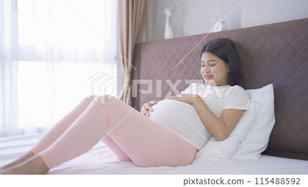 A Portrait of happy Asian pregnant woman in bedroom at home. Having a baby. Family people lifestyle. Love. A Portrait of happy Asian pregnant woman in bedroom at home. Having a baby. Family people lifestyle. Love. 115488592