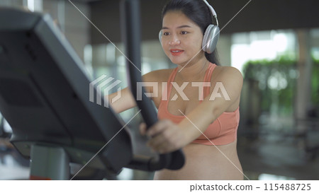 A portrait of happy Asian pregnant woman at gym fitness center club. Having a baby. Training workout. Exercise indoor with sport equipment. Athletic. Family people lifestyle. Mom love. Recreation. 115488725
