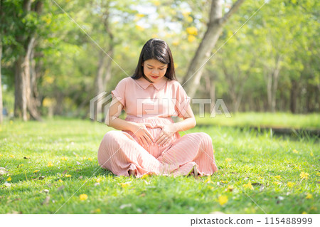 A portrait of happy Asian pregnant woman walking in public garden park on vacation. Love of mother. Having a baby. Family people lifestyle. A portrait of happy Asian pregnant woman walking in public garden park on vacation. Love of mother. Having a baby. Family people lifestyle. 115488999