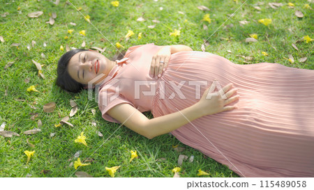A portrait of happy Asian pregnant woman walking in public garden park on vacation. Love of mother. Having a baby. Family people lifestyle. 115489058