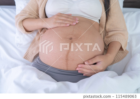 Close up of a Portrait of happy pregnant woman in bedroom at home. Having a baby. Family people lifestyle. Mom love. Close up of a Portrait of happy pregnant woman in bedroom at home. Having a baby. Family people lifestyle. Mom love. 115489063