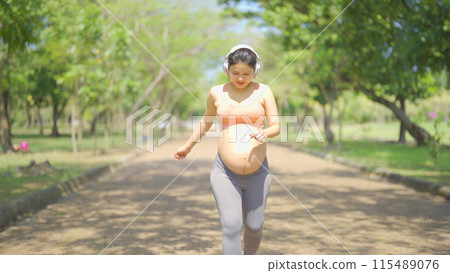 A portrait of happy Asian pregnant woman in yoga class club doing exercise at public garden park. Outdoor sport and recreation. activity with nature trees view. Having a baby. Family people lifestyle. 115489076