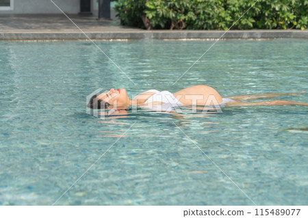 A portrait of happy Asian pregnant woman by the swimming pool. People lifestyle in travel holiday vacation concept. Relaxation. Having a baby. Family people lifestyle. Mom love. A portrait of happy Asian pregnant woman by the swimming pool. People lifestyle in travel holiday vacation concept. Relaxation. Having a baby. Family people lifestyle. Mom love. 115489077