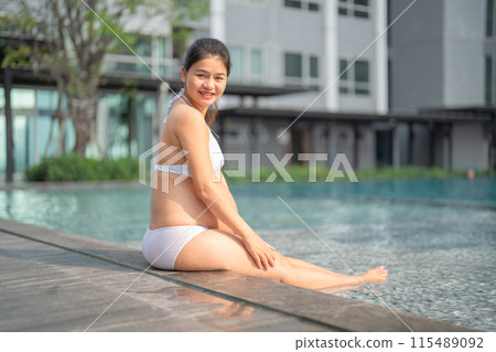 A portrait of happy Asian pregnant woman by the swimming pool. People lifestyle in travel holiday vacation concept. Relaxation. Having a baby. Family people lifestyle. Mom love. A portrait of happy Asian pregnant woman by the swimming pool. People lifestyle in travel holiday vacation concept. Relaxation. Having a baby. Family people lifestyle. Mom love. 115489092