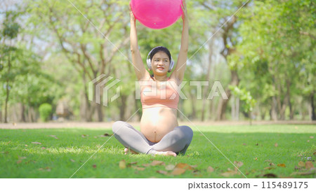 A portrait of happy Asian pregnant woman in yoga class club doing exercise at public garden park. Outdoor sport and recreation. activity with nature trees view. Having a baby. Family people lifestyle. 115489175