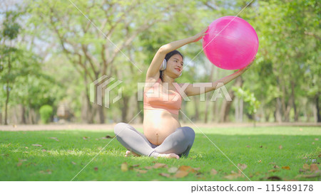 A portrait of happy Asian pregnant woman in yoga class club doing exercise at public garden park. Outdoor sport and recreation. activity with nature trees view. Having a baby. Family people lifestyle. A portrait of happy Asian pregnant woman in yoga class club doing exercise at public garden park. Outdoor sport and recreation. activity with nature trees view. Having a baby. Family people lifestyle. 115489178