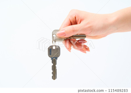 Woman's hand holding a house key 115489283