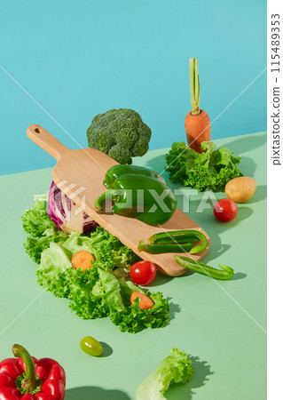 Advertising photo of products has organic ingredients against blue background. Vegetables scattered lay on green table top with a wooden chopping board decoration, blank space for text 115489353