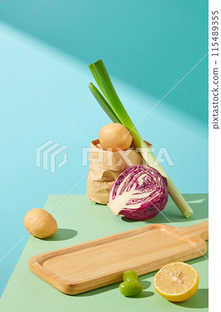 From above view shot photo with an empty wooden tray displayed on green kitchen table, decorated by fresh vegetables around, against blue texture. Blank space for product placement and adding text From above view shot photo with an empty wooden tray displayed on green kitchen table, decorated by fresh vegetables around, against blue texture. Blank space for product placement and adding text 115489355