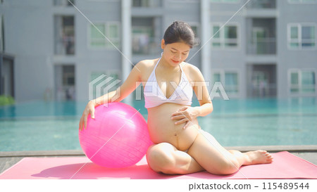 A portrait of happy Asian pregnant woman by the swimming pool. People lifestyle in travel holiday vacation concept. Relaxation. Having a baby. Family people lifestyle. Mom love. A portrait of happy Asian pregnant woman by the swimming pool. People lifestyle in travel holiday vacation concept. Relaxation. Having a baby. Family people lifestyle. Mom love. 115489544