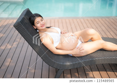 A portrait of happy Asian pregnant woman by the swimming pool. People lifestyle in travel holiday vacation concept. Relaxation. Having a baby. Family people lifestyle. Mom love. 115489565