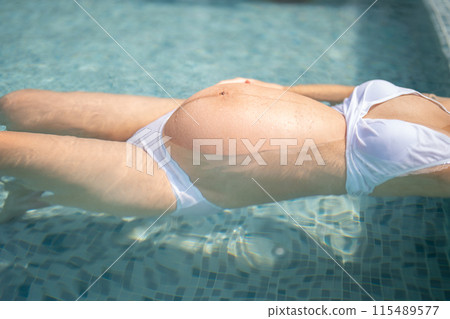 A portrait of happy Asian pregnant woman by the swimming pool. People lifestyle in travel holiday vacation concept. Relaxation. Having a baby. Family people lifestyle. Mom love. A portrait of happy Asian pregnant woman by the swimming pool. People lifestyle in travel holiday vacation concept. Relaxation. Having a baby. Family people lifestyle. Mom love. 115489577