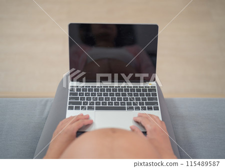 A portrait of happy Asian pregnant woman using, working online with computer laptop notebook tablet device with screen in bedroom at home. Having a baby. Family people lifestyle. Mom love. A portrait of happy Asian pregnant woman using, working online with computer laptop notebook tablet device with screen in bedroom at home. Having a baby. Family people lifestyle. Mom love. 115489587