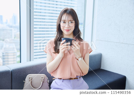 Woman drinking coffee on the sofa in the office 115490356