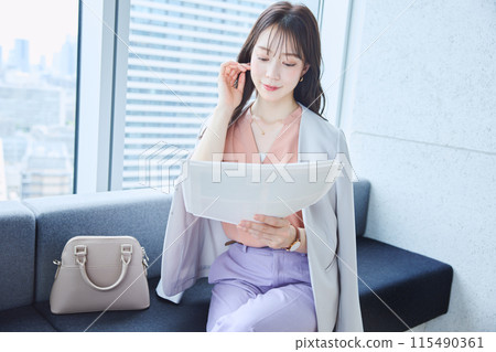 一位女士在辦公室的沙發上查看文件 115490361