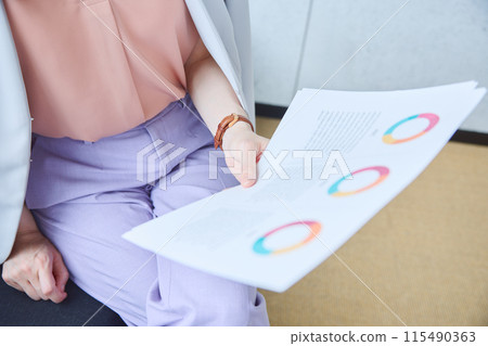 A woman looking at documents on a sofa in an office A woman looking at documents on a sofa in an office 115490363