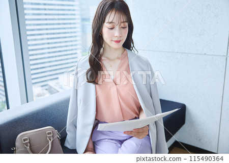 A woman looking at documents on a sofa in an office A woman looking at documents on a sofa in an office 115490364
