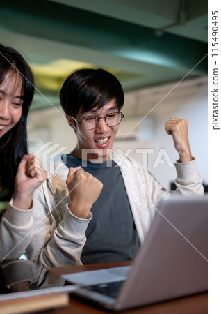 A young, cheerful Asian male college student celebrating good news with his friend. 115490495
