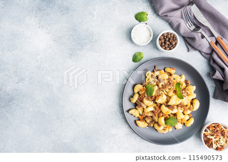 Stewed pasta with minced beef and vegetables, macaroni in Navy style on a plate. grey concrete background. Copy space. Stewed pasta with minced beef and vegetables, macaroni in Navy style on a plate. grey concrete background. Copy space. 115490573