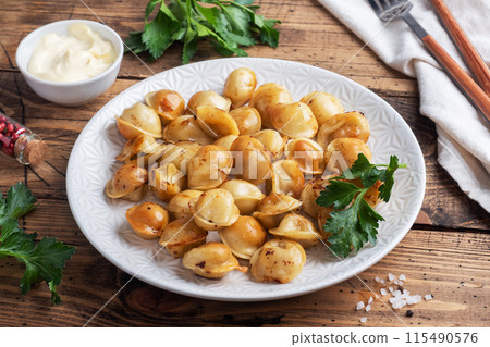 Traditional fried pelmeni, ravioli, dumplings filled with meat on plate, russian kitchen. Wooden rustic table, copy space. 115490576