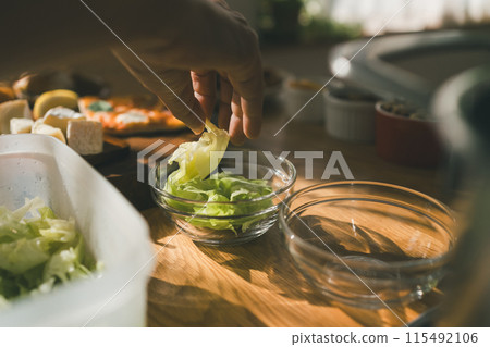將撕碎的生菜放入玻璃沙拉碗的食品儲存容器中。 將撕碎的生菜放入玻璃沙拉碗的食品儲存容器中。 115492106