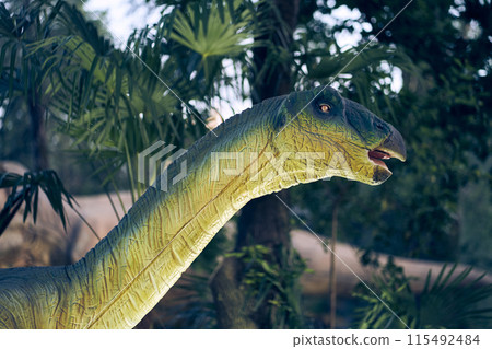 Dinosaur head close-up in the park. Giant Therizinosaurus on display in the park on a summer day in dense vegetation with space to copy. High quality photo Dinosaur head close-up in the park. Giant Therizinosaurus on display in the park on a summer day in dense vegetation with space to copy. High quality photo 115492484