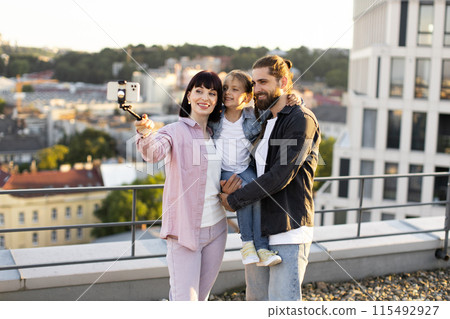 Happy family taking selfie together on rooftop with city view 115492927