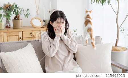 A woman sneezing and holding her mouth 115493023