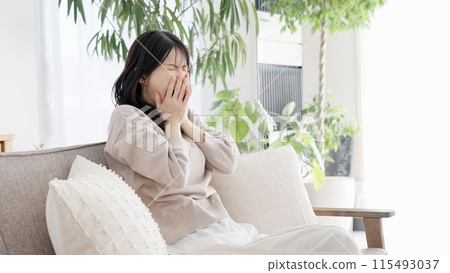 Woman yawning in the living room Woman yawning in the living room 115493037