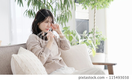 Woman crying in the living room Woman crying in the living room 115493038