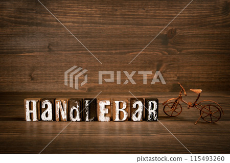HANDLEBAR. Word from alphabet blocks and rusty miniature bicycle on wood texture background HANDLEBAR. Word from alphabet blocks and rusty miniature bicycle on wood texture background 115493260