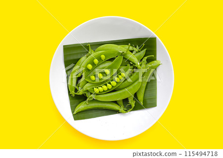 Fresh young green peas on yellow background. Fresh young green peas on yellow background. 115494718