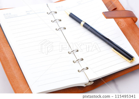 某人打開環形筆記本進行辦公桌工作的圖像 115495341