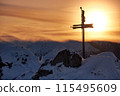 Majestic sunset over snowy mountain peak with cross silhouette, creating peaceful winter landscape 115495609