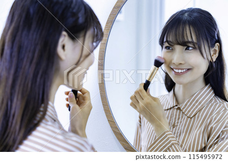 Young woman doing make-up while looking in the mirror 115495972