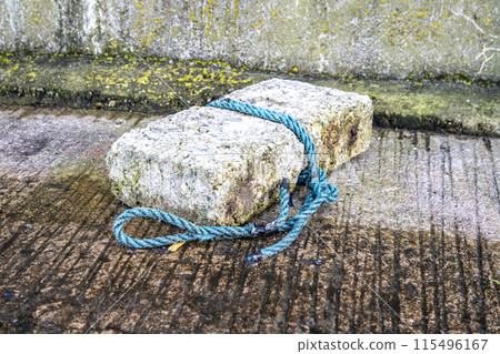 Rope tied to stone for fishing at harbour Rope tied to stone for fishing at harbour 115496167