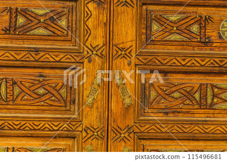 Big old wooden door decorated with various symbolic signs carved directly on the canvas of massif. Example of exterior and interior decoration of entrance lobbies in different cultures around world Big old wooden door decorated with various symbolic signs carved directly on the canvas of massif. Example of exterior and interior decoration of entrance lobbies in different cultures around world 115496681