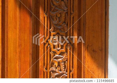 Big old wooden door decorated with various symbolic signs carved directly on the canvas of massif. Example of exterior and interior decoration of entrance lobbies in different cultures around world Big old wooden door decorated with various symbolic signs carved directly on the canvas of massif. Example of exterior and interior decoration of entrance lobbies in different cultures around world 115496685