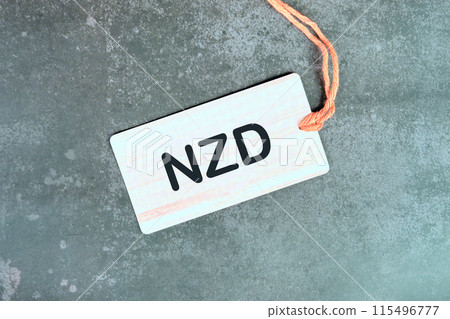 NZD sign text written on a light card on a gray background. View from above 115496777