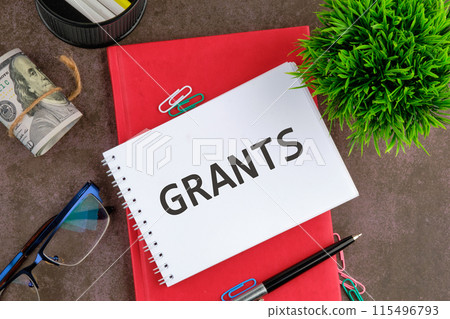 GRANT word, text written on a blank sheet of notepad next to the business supplies 115496793