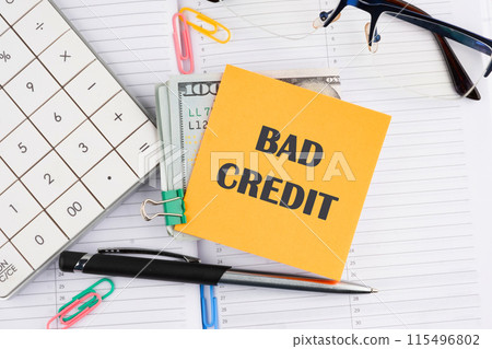 Business concept. Bad Credit written on a yellow sticker with money on a business notebook 115496802